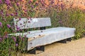 Wooden garden bench among verbena plants in full bloom.