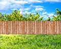 Wooden garden fence at backyard, green grass and blue sky with white clouds Royalty Free Stock Photo