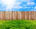Wooden garden fence at backyard, green grass and blue sky with white clouds