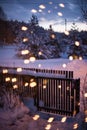 Wooden garden gate on a cold and snowy winter night with bokeh Christmas lights on the foreground Royalty Free Stock Photo