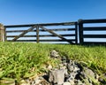 Wooden Gate, blue sky, rocks and green grass under sunshiny day. Royalty Free Stock Photo