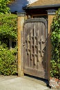 Wooden gate with brick pillars and front yard trees and shrubs with suburban house or home background in late afternoon Royalty Free Stock Photo