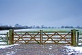 Wooden gate next to a wintery field with black sheep