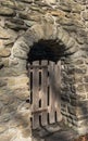 A wooden gate in a stone wall entranceway on a sunny winter day