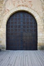 The gates of an old medieval castle or fortress, covered with strips of iron. The gate has a closed wicket with a handle Royalty Free Stock Photo