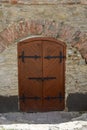 The gates of an old medieval castle or fortress, covered with strips of iron. The gate has a closed wicket with a handle Royalty Free Stock Photo