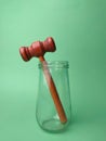 Wooden gavel on glass jar on a green background Royalty Free Stock Photo