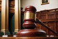 A wooden gavel sits on a wooden table in front of a judge\'s bench