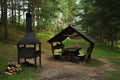 Wooden gazebo next to a barbecue and firewood in the forest Royalty Free Stock Photo
