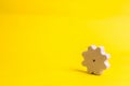 A wooden gear on a yellow background. The concept of technology and business processes. Minimalism. Mechanisms and devices. Work,