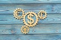 Wooden gears with dollar currency signs