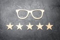Wooden glasses and five stars on a concrete background. High quality glasses. The best optics. Correction of vision
