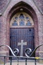 Wooden gothic church door behind an iron gate with cross