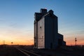 Wooden grain elevator and tracks against prairie sunset