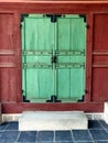 A wooden green door with red wall with an old ancient lock