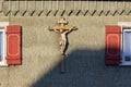 wooden green facade with crucifix and red color shutter of bavarian farmhouse