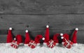 Wooden grey christmas background with red santa hats and gifts. Royalty Free Stock Photo