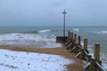 Wooden groyne on a snowy pebble beach