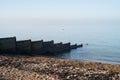 Wooden groyne water breakers on a pebble beach in Whitstable on a bright but slightly hazy winter day