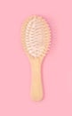 Wooden hairbrush made of natural oak on pastel pink background