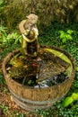 A wooden half barrel water fountain, garden feature, with statue Royalty Free Stock Photo