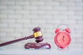 Wooden hammer and retro pink alarm clock on wood table,white brick wall background in the auction room,Business concept and Royalty Free Stock Photo