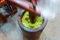 Wooden hammer Smashing on green rice for cooking Thai sweet cereal bat (Krayasart)