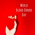 Wooden hand with big red heart in a giving gesture. World Blood Donor Day wording