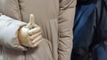 The wooden hand of a doll, a mannequin shows super gesture, thumbs up. The mannequin in store is wearing a warm jacket