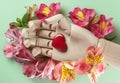 wooden hand in flowers holds a heart