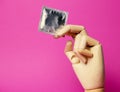 Wooden hand holding blank mock up condom pack pink background Royalty Free Stock Photo