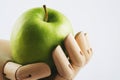 Wooden hand holding a granny smith apple on a white background Royalty Free Stock Photo