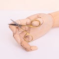 Wooden hand holding scissors for cutting nail Royalty Free Stock Photo