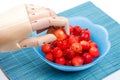 Wooden hand prosthetic takes cherry from plate on bamboo mat with ripe berries covered by water droplets