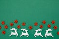 Wooden handmade Christmas decorations white Deers and red Stars with a pattern on a green isolated background. Flat lay, top view Royalty Free Stock Photo