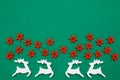 Wooden handmade Christmas decorations white Deers and red Stars with a pattern on a green isolated background. Flat lay, top view Royalty Free Stock Photo