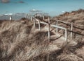 Wooden handrails surrounded by dry grass and Talacre Lighthouse in the background. North Wales. Royalty Free Stock Photo