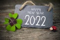 Wooden hang tag and slate with four leaf clover and sparklers with happy new year 2022 on wooden weathered background Royalty Free Stock Photo