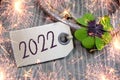Wooden hang tag and slate with four leaf clover and sparklers with happy new year 2022 on wooden weathered background Royalty Free Stock Photo