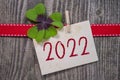 Wooden hang tag and slate with four leaf clover and sparklers with happy new year 2022 on wooden weathered background Royalty Free Stock Photo