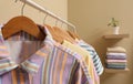 Wooden hangers with stylish clothes on rack near beige wall. Dressing room interior Royalty Free Stock Photo