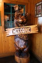 A Wooden Happy Bear welcomes with wave of his paw