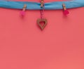 Wooden heart hanging on a blue ribbon with clothespins on a pink background. Congratulatory postcard. Copy space, Royalty Free Stock Photo