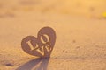 Wooden heart with inscription Love on seaside at dawn