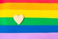 Wooden heart on lgbtq flag background, top view