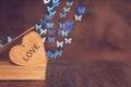 Wooden heart with an old book on the table and a background of bokeh made of butterflies. Valentine`s Day. Royalty Free Stock Photo