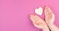 Wooden heart on a pink colored background, empty copy space for text, greeting card, open hands Royalty Free Stock Photo