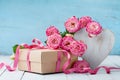 Wooden heart, pink rose flowers and gift box on turquoise table. Beautiful greeting card for Birthday, Woman or Mothers Day.