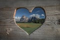 Wooden heart shape with meadows at Alpe di Siusi during summer with view to mountains of Plattkofel and Langkofel in the Dolomite Royalty Free Stock Photo