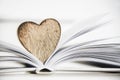 Wooden heart shape on a open book. Love reading concept close up. Royalty Free Stock Photo